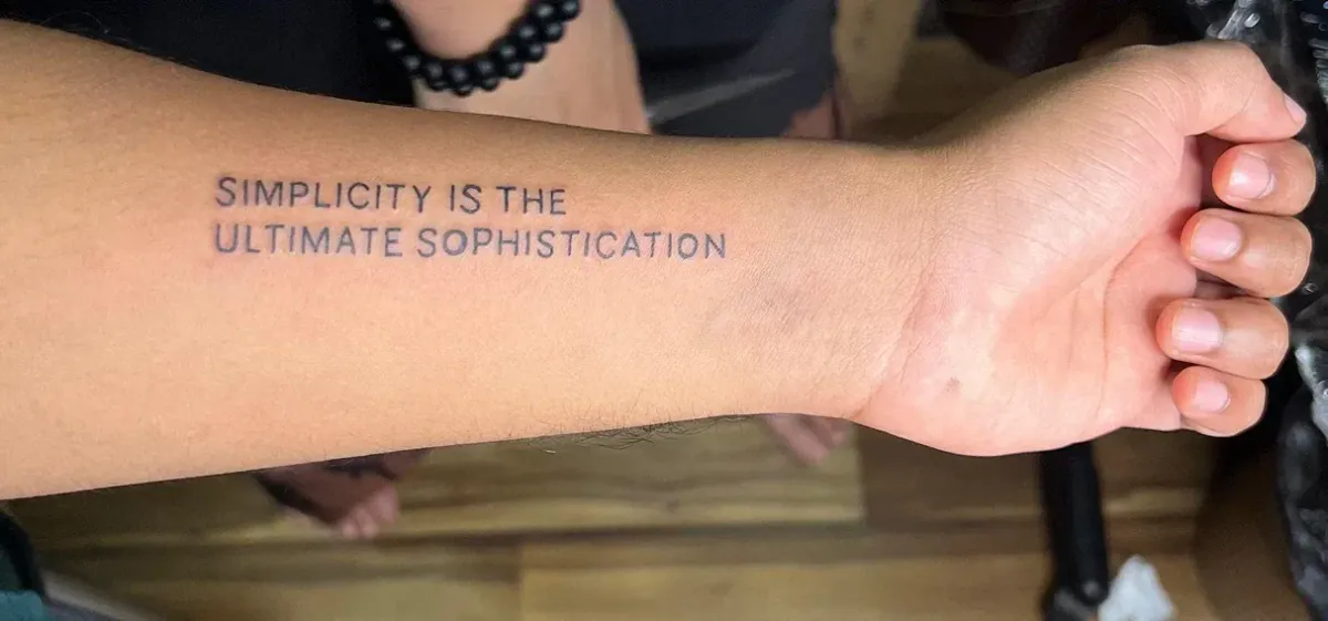 Forearm tattoo reading Simplicity is the ultimate sophistication
