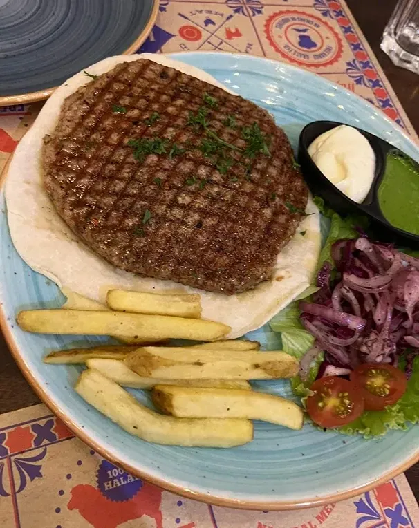 Grilled steak with fries and salad on a blue plate