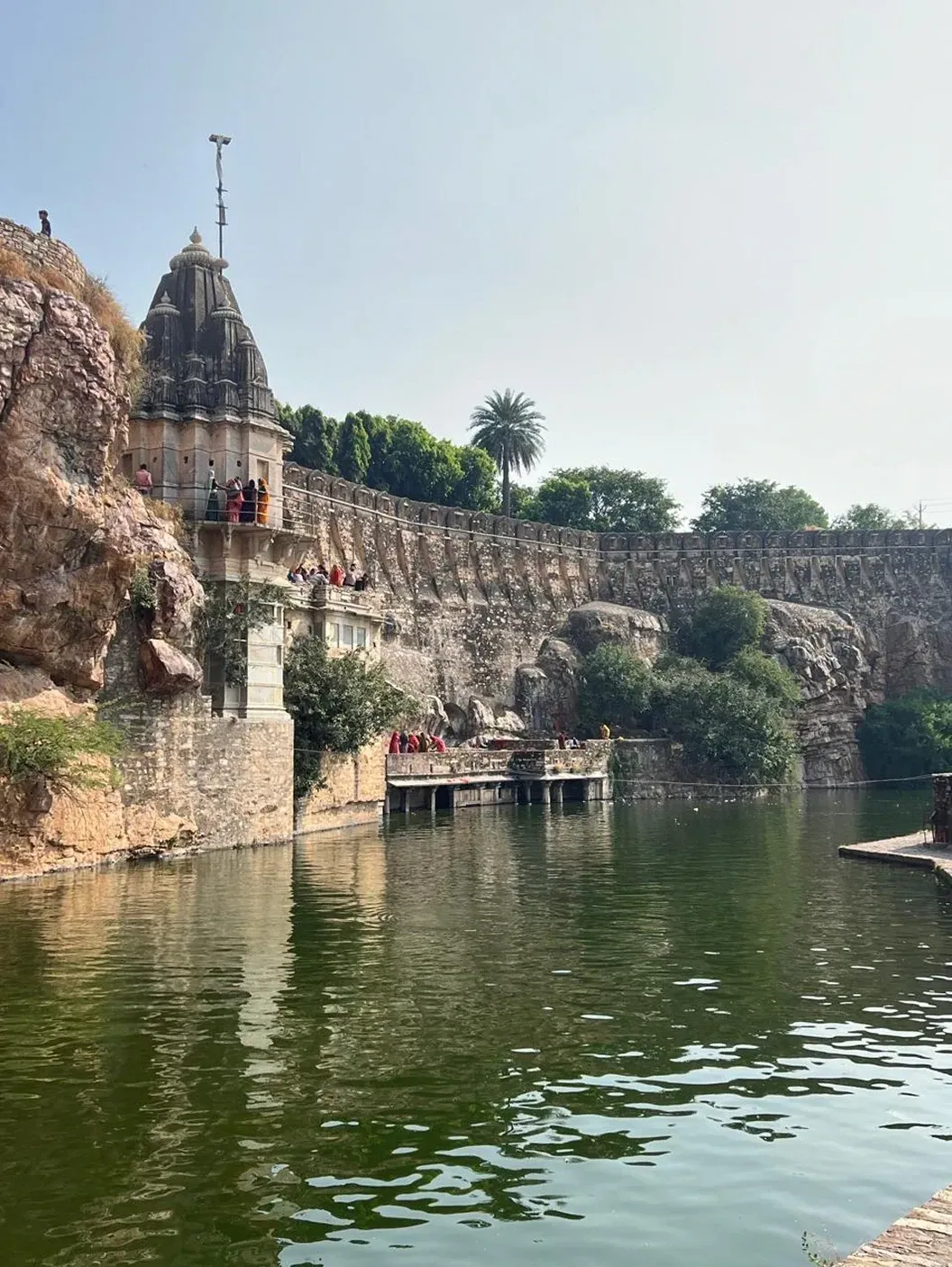 Old stone temple and fort walls beside a green lake