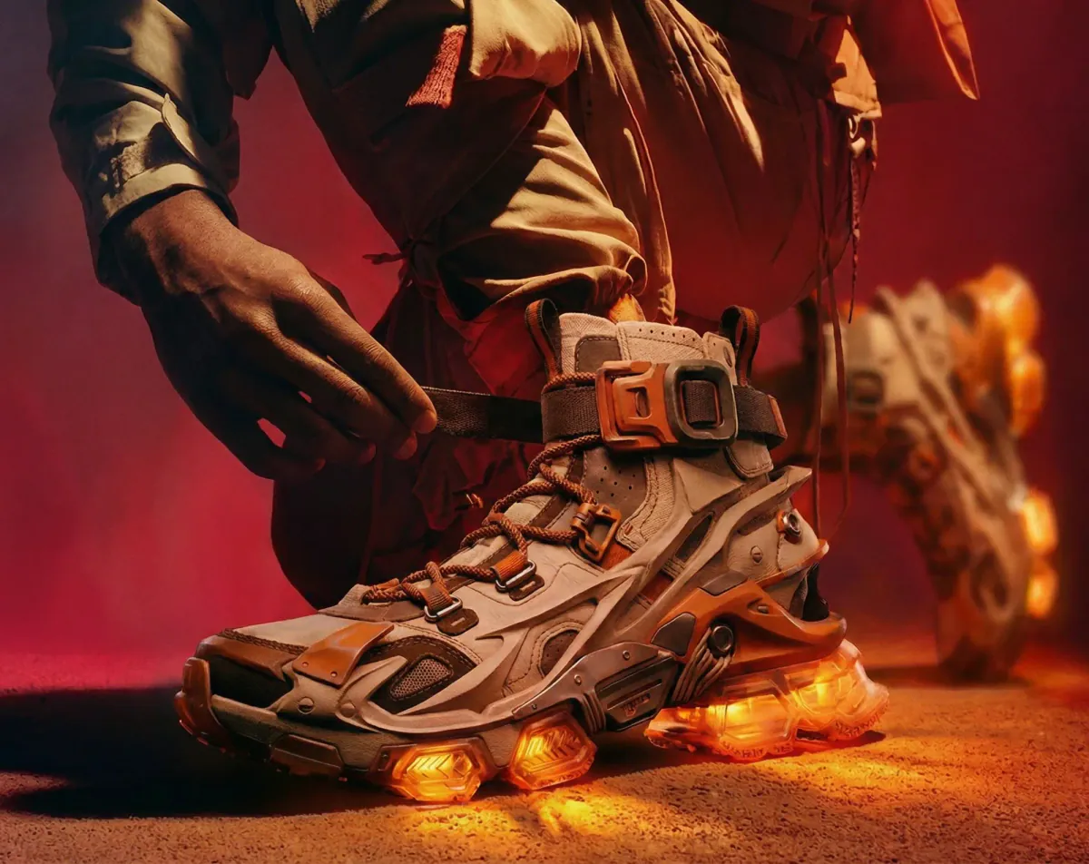 Hands fastening the strap of a sneaker with glowing orange soles on red ground