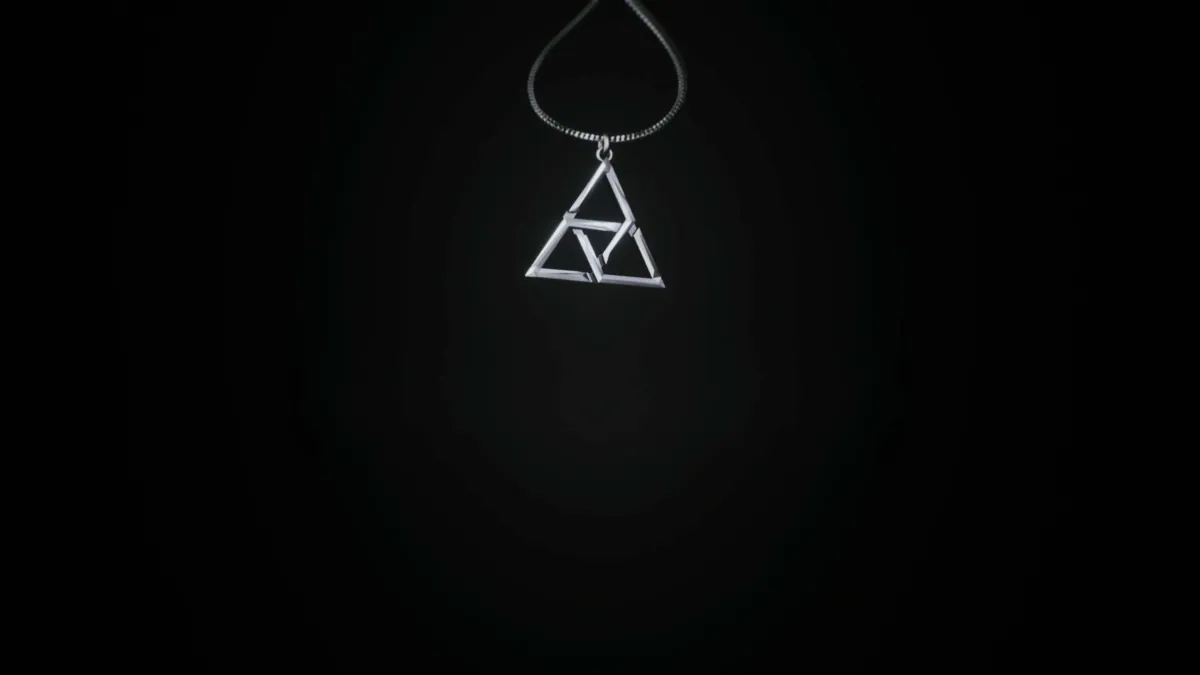 Small triangle pendant hanging from a chain in the dark