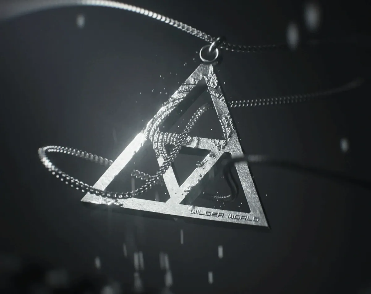 Silver triangle pendant with its chain looping around it on a dark background